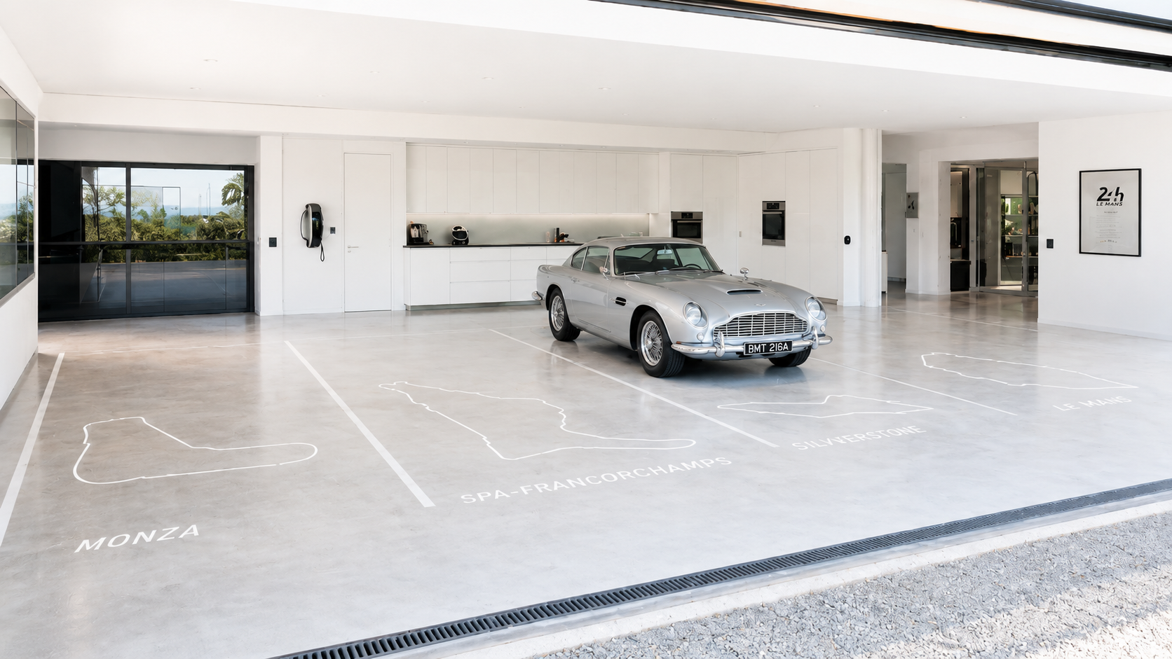 Garage de collection avec tracés de circuits mythiques gravés au sol — vue de jour