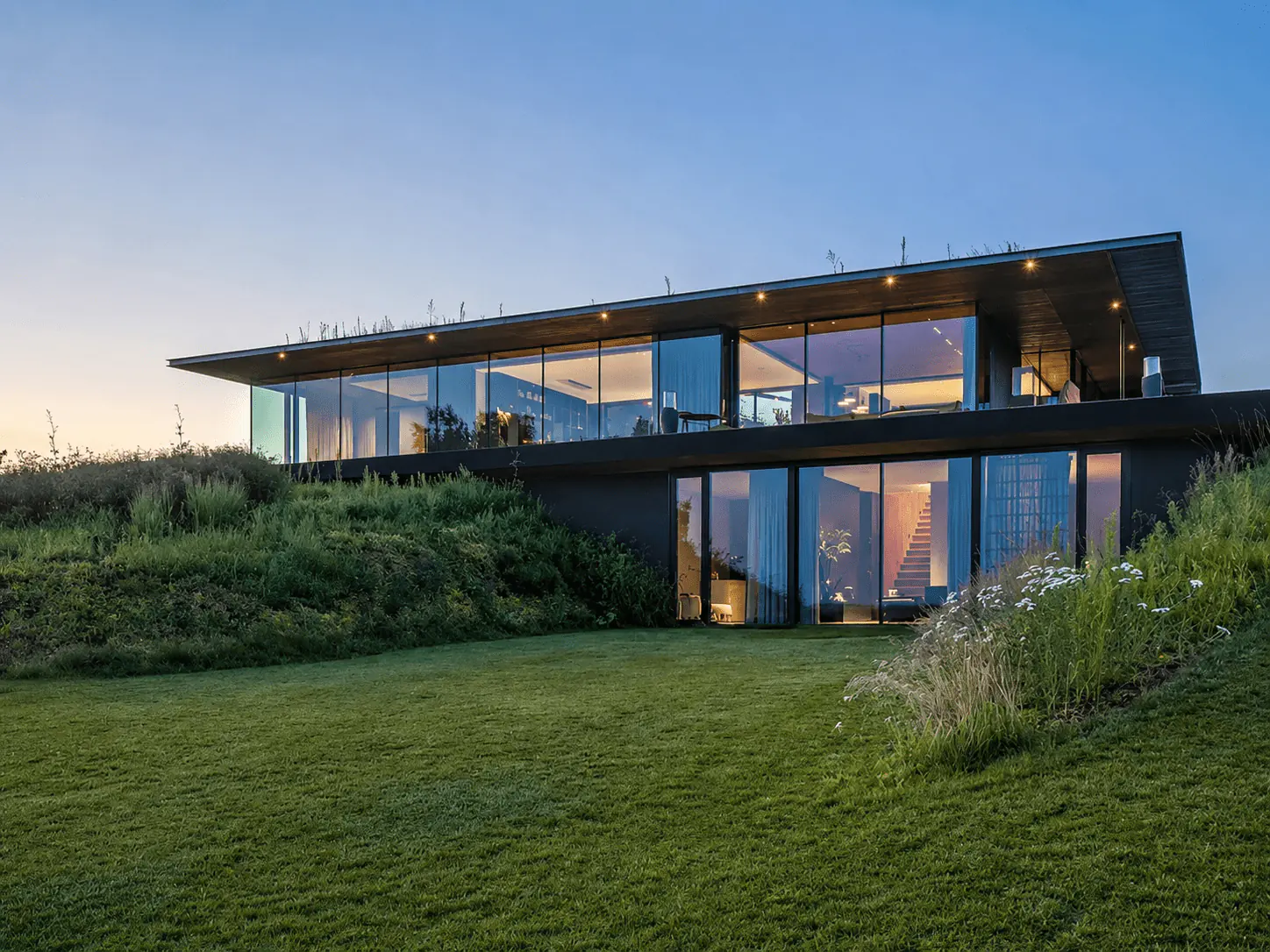 Villa contemporaine au crépuscule, baies vitrées éclairées — visuel Invest Prestige